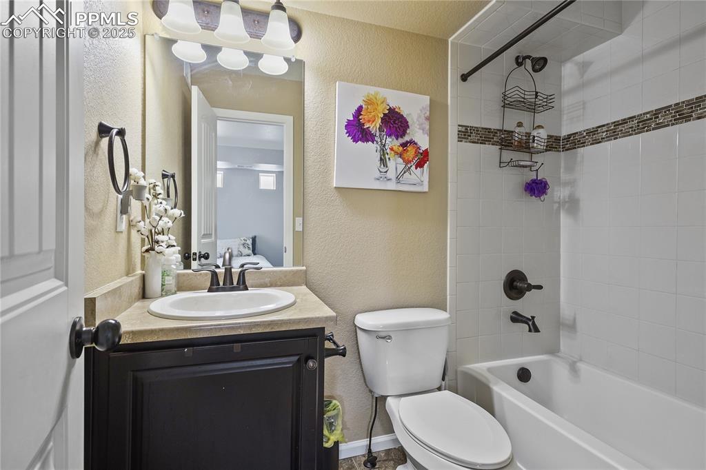 Image 25 of 38: Full bathroom with toilet, vanity, and tiled shower / bath combo