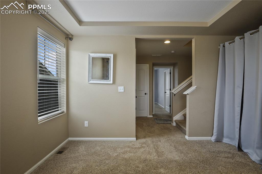 Image 27 of 38: Empty room with a tray ceiling and light carpet