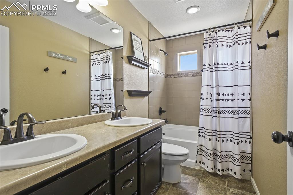 Image 28 of 38: Full bathroom featuring a textured ceiling, vanity, shower / tub combo, and