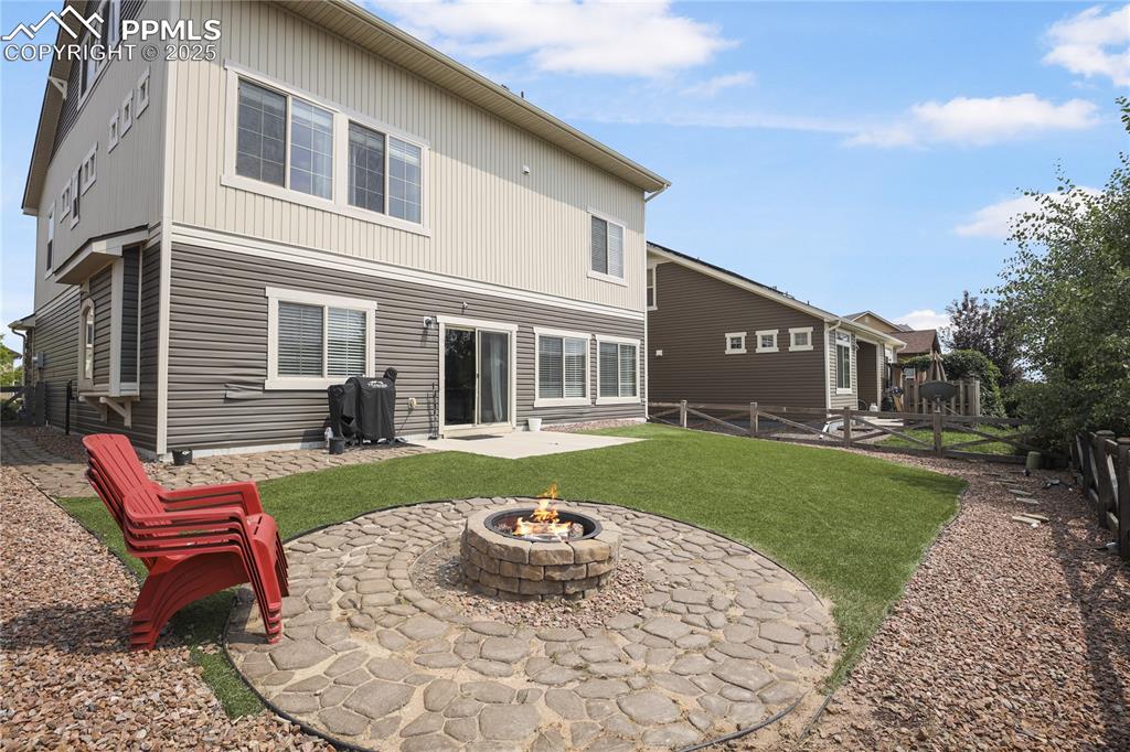 Image 6 of 38: Back of property featuring a fire pit, a yard, and a patio
