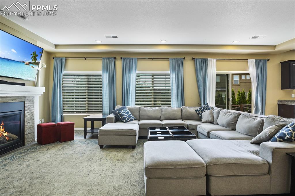 Image 9 of 38: Carpeted living room featuring a fireplace and a textured ceiling