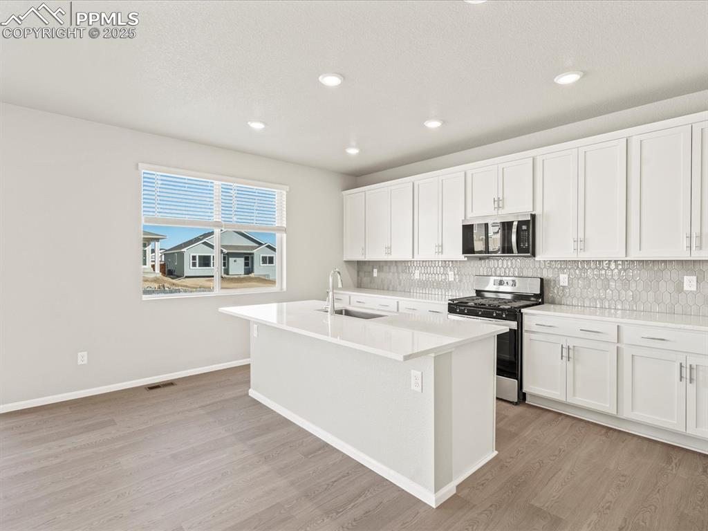 Image 10 of 26: Kitchen with white cabinets, appliances with stainless steel finishes, a ki