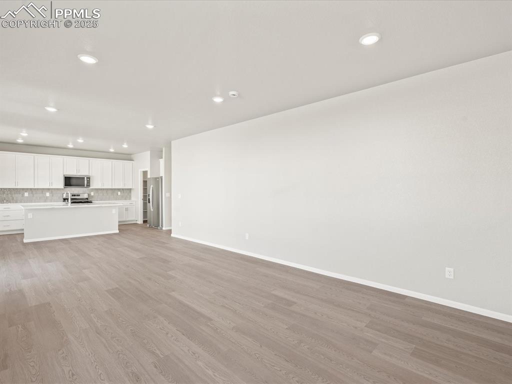Image 11 of 26: Unfurnished living room with light wood-style flooring and recessed lightin