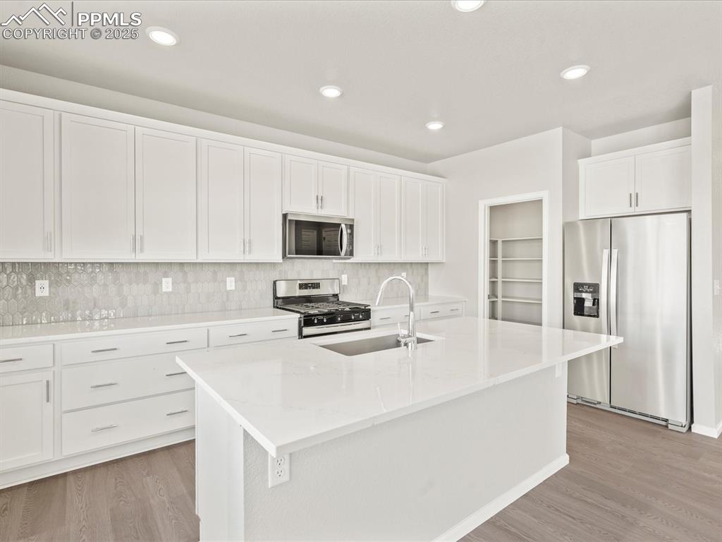 Image 3 of 26: Kitchen featuring appliances with stainless steel finishes, white cabinetry