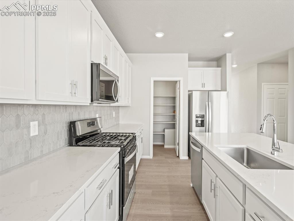 Image 5 of 26: Kitchen featuring appliances with stainless steel finishes, white cabinets,