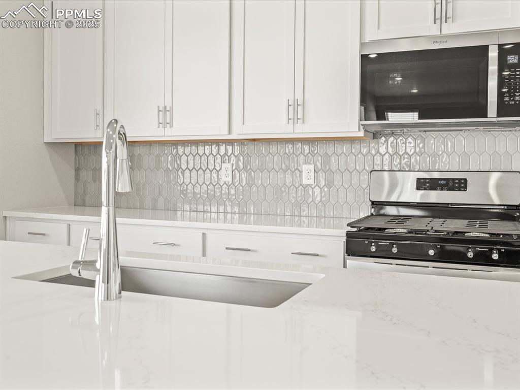 Image 8 of 26: Kitchen with white cabinetry, appliances with stainless steel finishes, dec