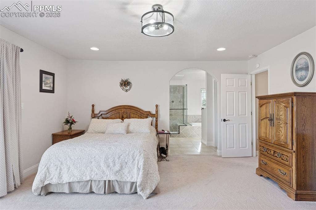 Image 23 of 50: Primary suite featuring light colored carpet, ensuite bath,  and recessed l