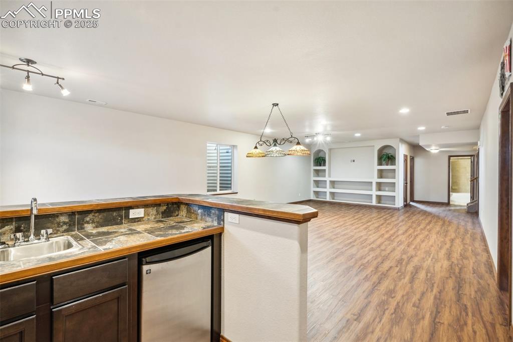 Image 34 of 50: Basement wet bar with sink and bar frig.