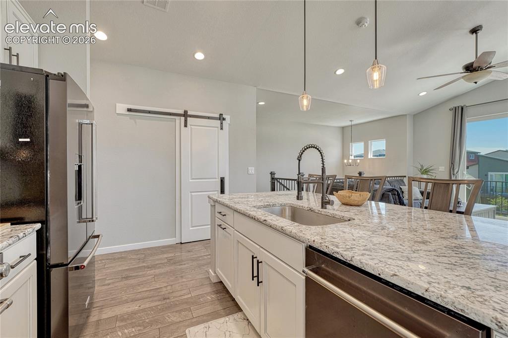 Image 16 of 30: Beautiful slab granite countertops and barn door on pantry.