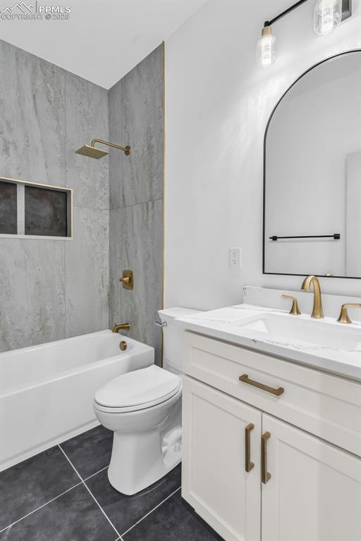 Image 17 of 39: Bathroom featuring vanity, shower / washtub combination, and dark tile patt