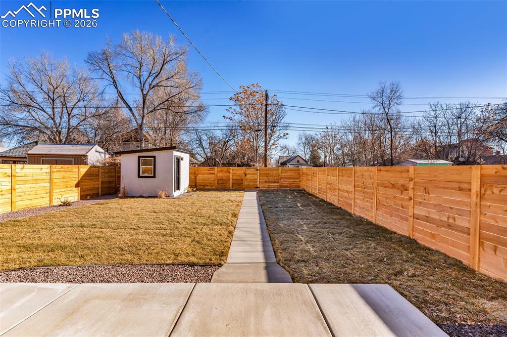 Image 22 of 39: Fenced backyard with an outdoor structure