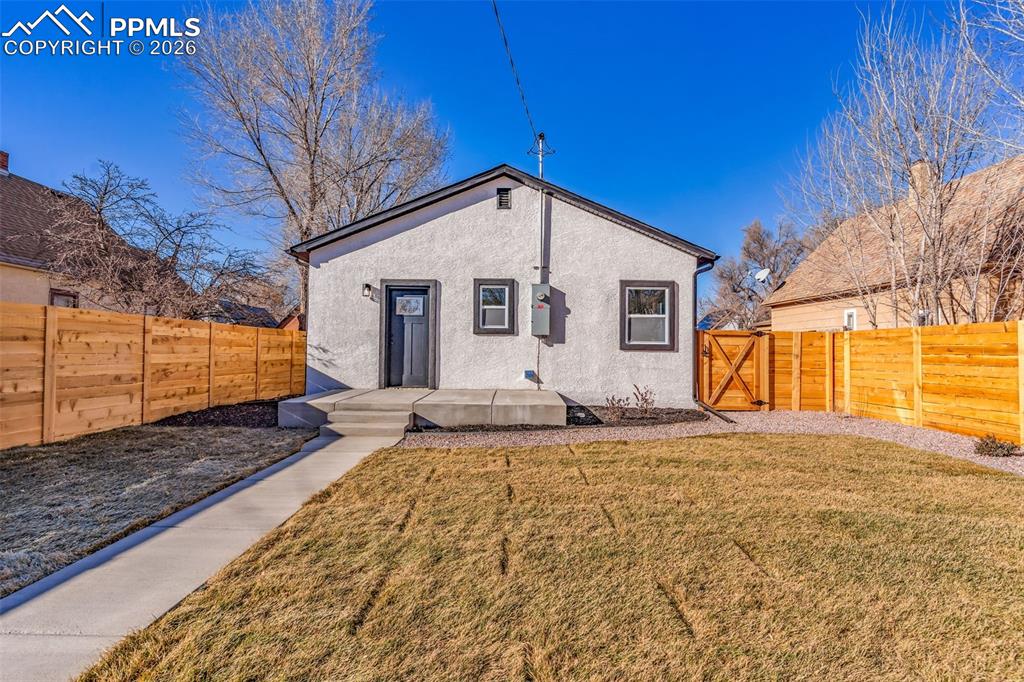 Image 24 of 39: Rear view of house with a gate, stucco siding, and a fenced backyard
