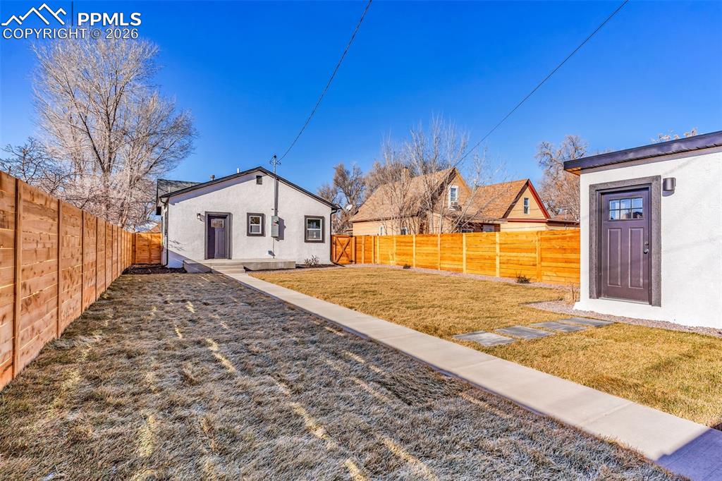 Image 25 of 39: Rear view of property featuring a fenced backyard and stucco siding