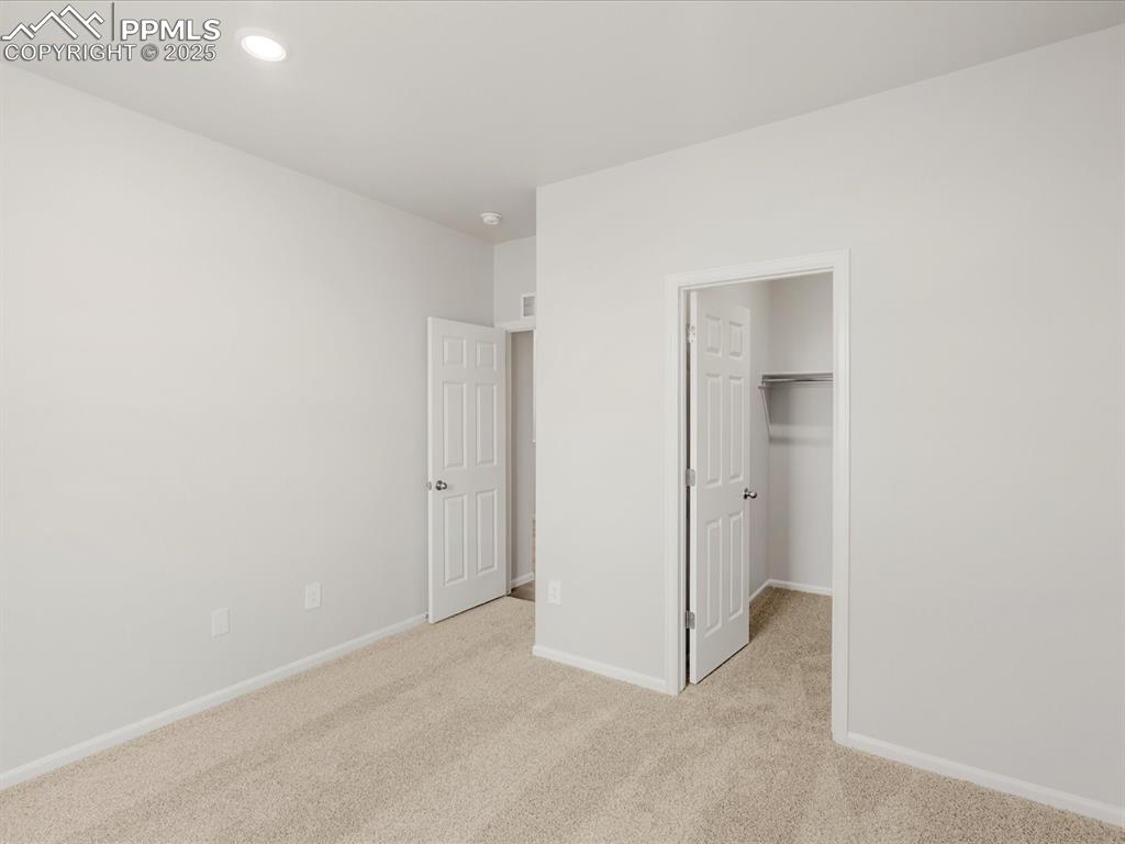 Image 15 of 40: Unfurnished bedroom featuring carpet, baseboards, a spacious closet, and re