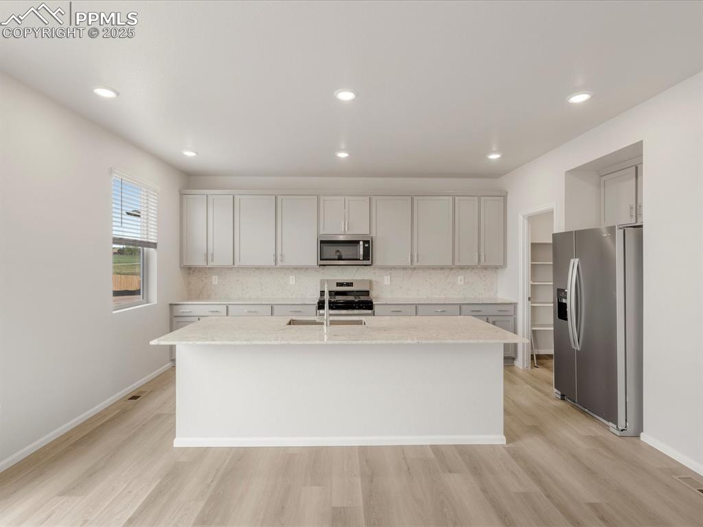 Image 2 of 40: Kitchen featuring appliances with stainless steel finishes, light wood-styl