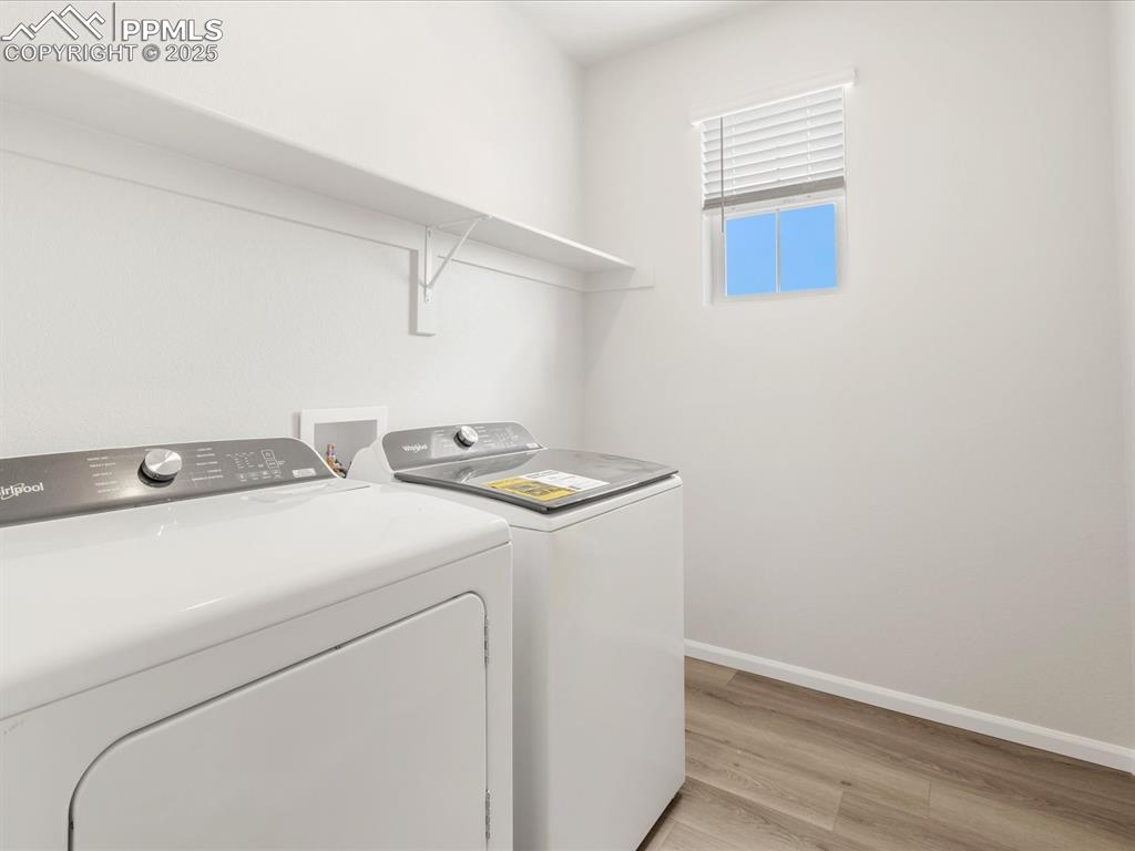 Image 29 of 40: Laundry room featuring separate washer and dryer, light wood-style flooring