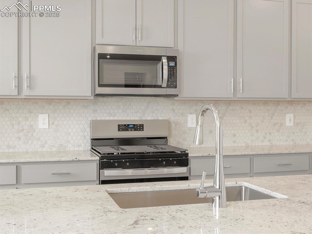 Image 3 of 40: Kitchen with appliances with stainless steel finishes, a sink, backsplash,