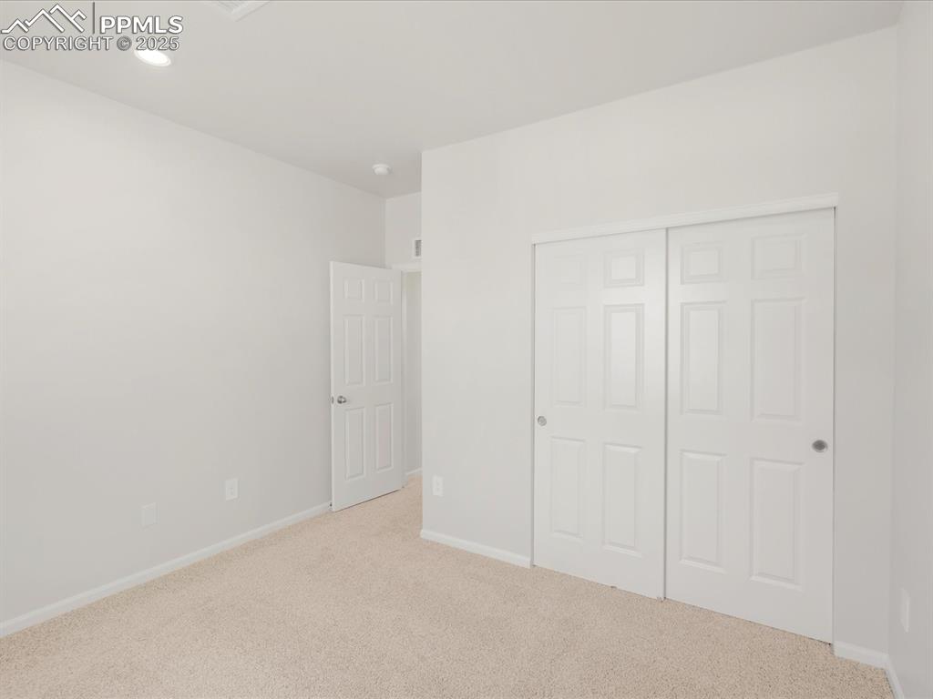 Image 36 of 40: Unfurnished bedroom with carpet, baseboards, a closet, and recessed lightin
