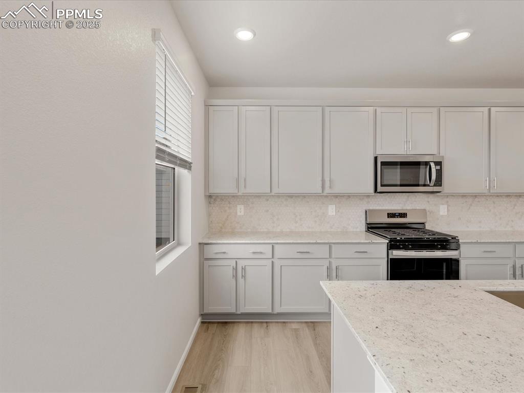 Image 4 of 40: Kitchen with appliances with stainless steel finishes, light wood finished
