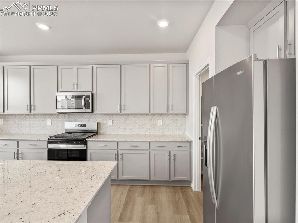 Image 5 of 40: Kitchen with appliances with stainless steel finishes, gray cabinets, light