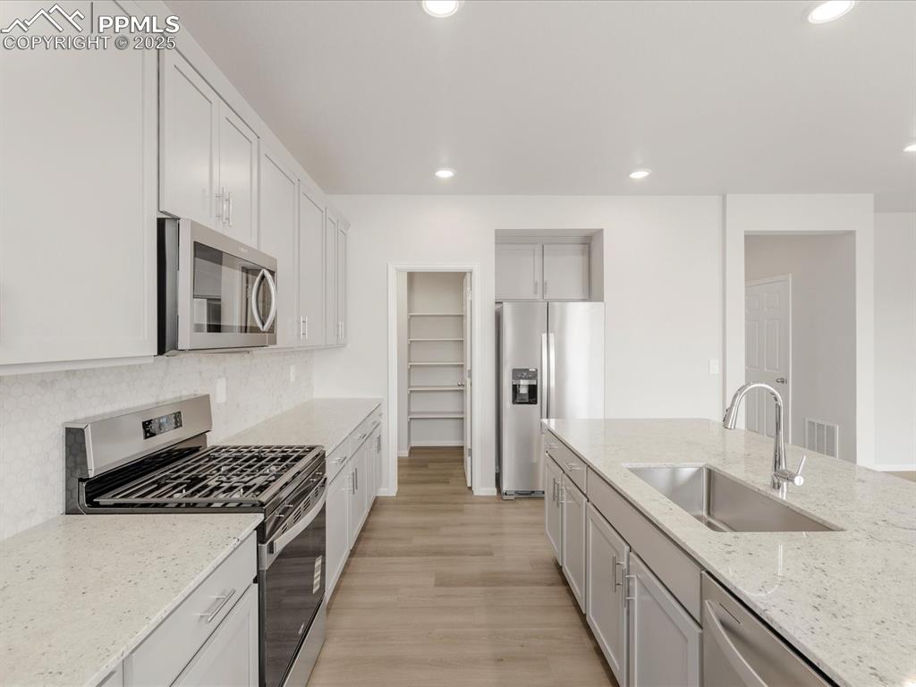Image 6 of 40: Kitchen featuring stainless steel appliances, a sink, decorative backsplash
