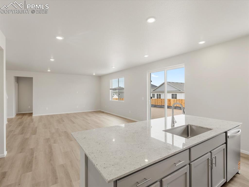 Image 7 of 40: Kitchen with a sink, dishwashing machine, an island with sink, light wood-s