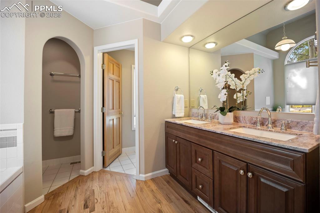 Image 16 of 33: Bathroom featuring light wood-type flooring, double vanity, and a bath
