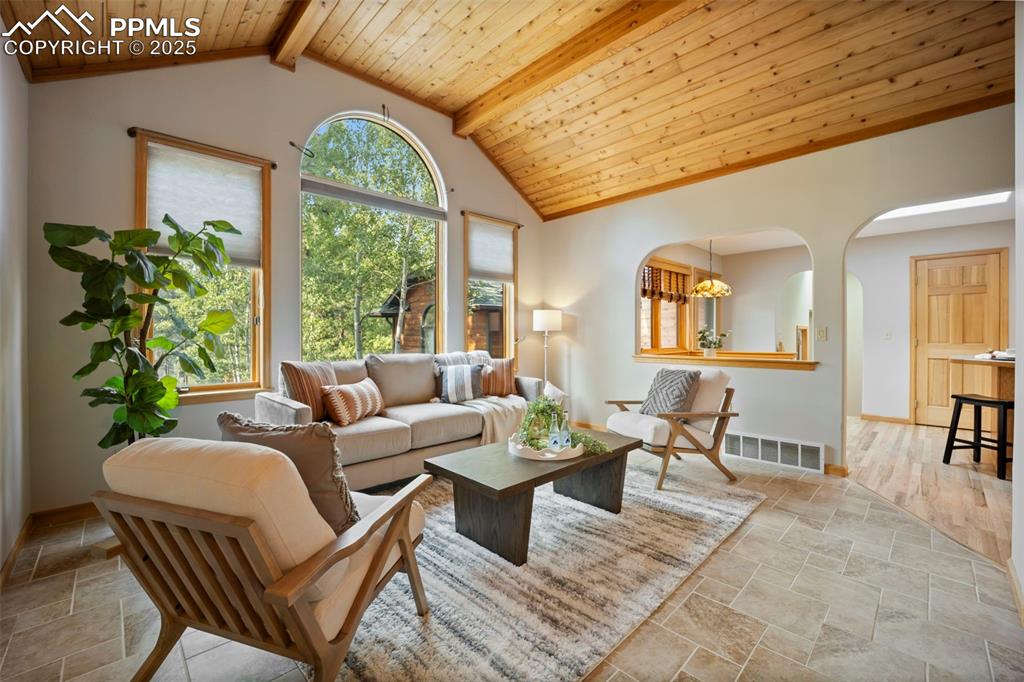 Image 2 of 33: Living area with a wood ceiling with exposed beams, arched walkways, light 