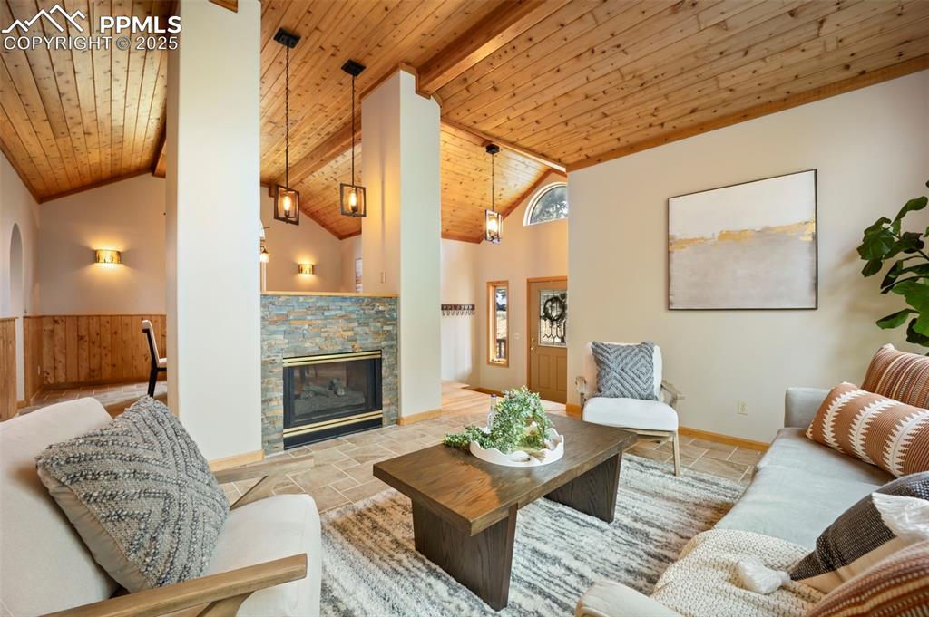 Image 4 of 33: Living room featuring a wooden ceiling with exposed beams, a stone fireplac