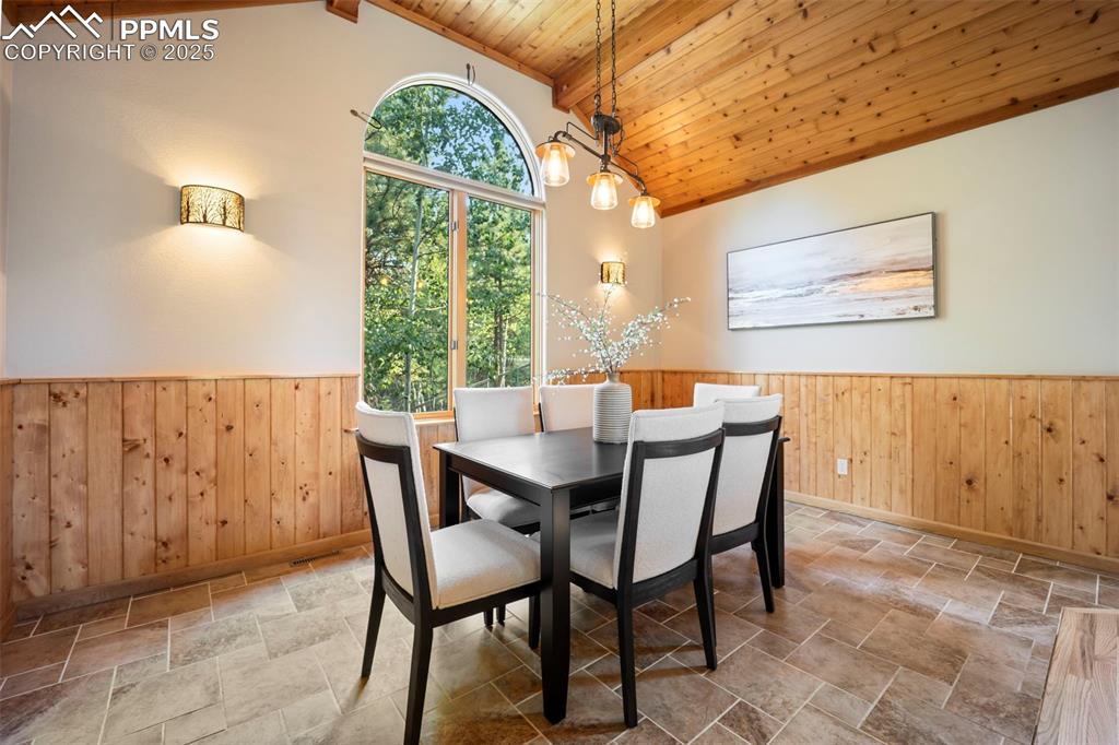 Image 5 of 33: Dining room with wood walls, a wainscoted wall, a wood ceiling with exposed