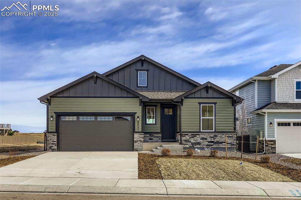 Image 1 of 28: Craftsman inspired home with stone siding, board and batten siding, concret