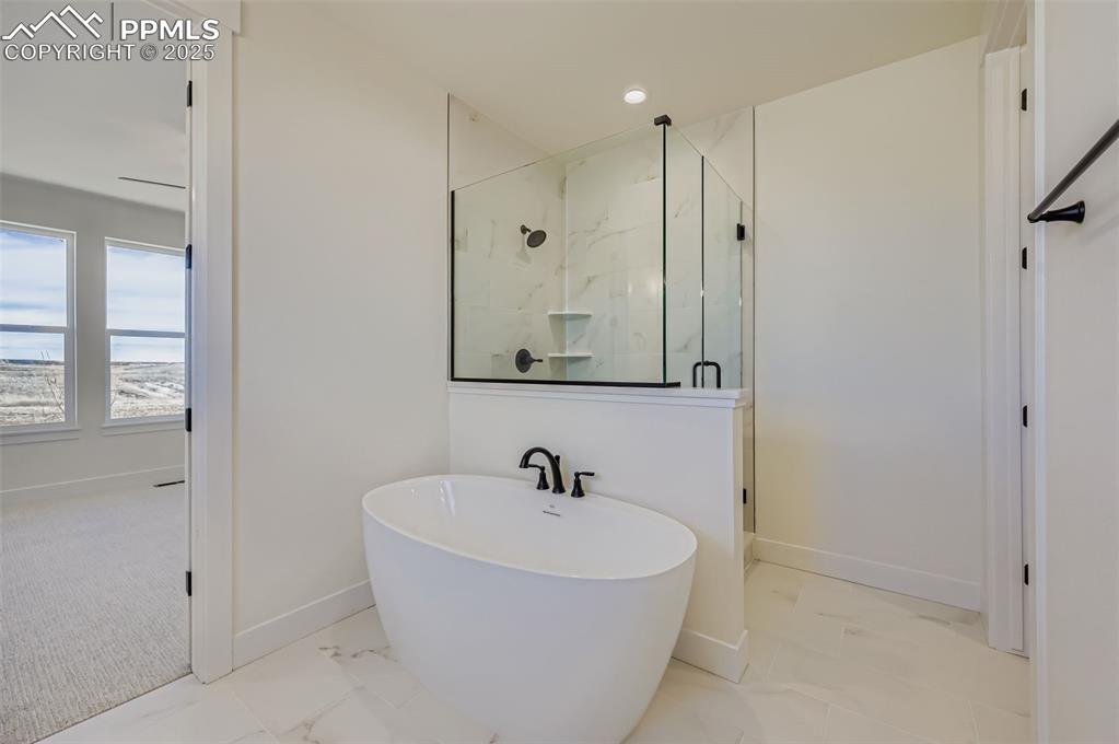 Image 13 of 28: Bathroom featuring a marble finish shower, a freestanding bath, light marbl