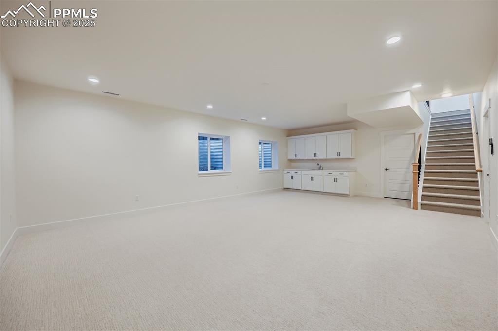 Image 18 of 28: Basement featuring stairs, light colored carpet, and recessed lighting