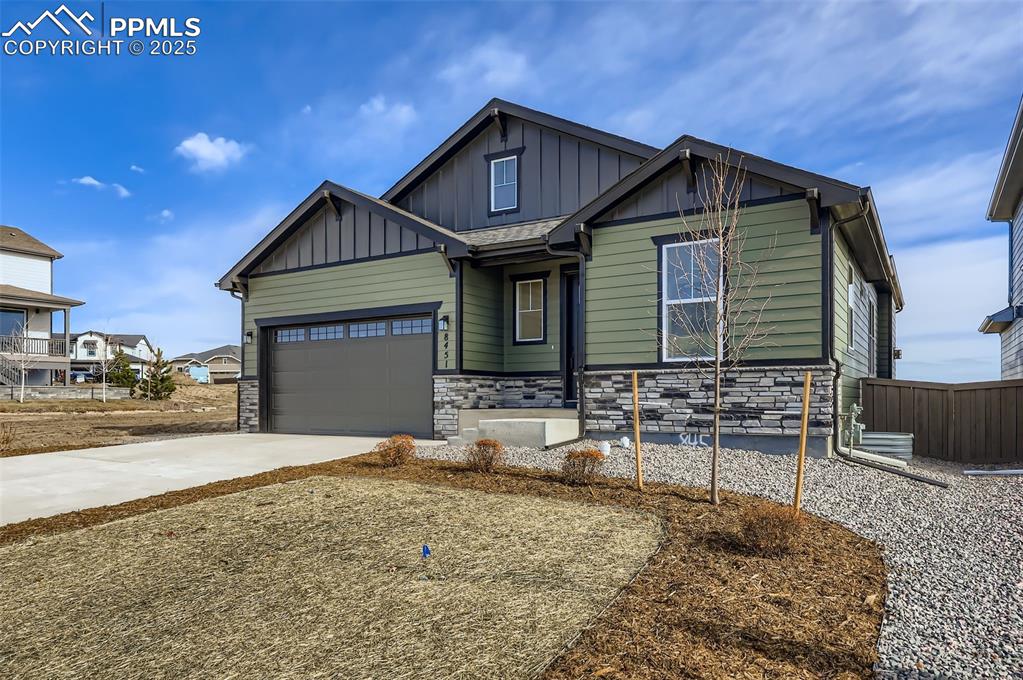 Image 2 of 28: Craftsman-style house with stone siding, board and batten siding, driveway,