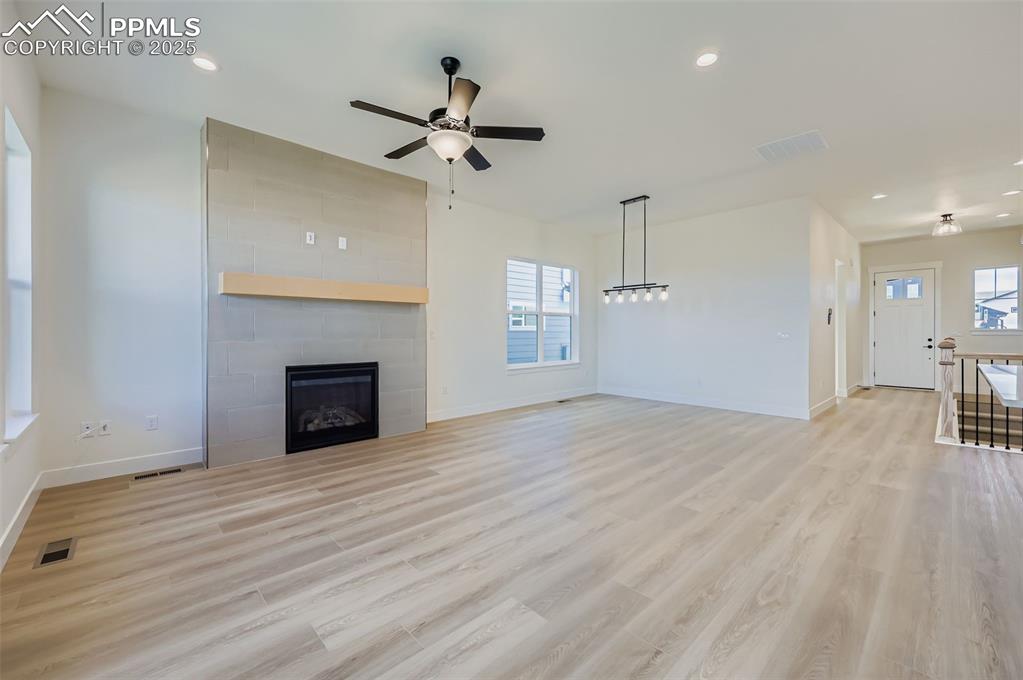 Image 5 of 28: Unfurnished living room featuring a tile fireplace, light wood-style floors