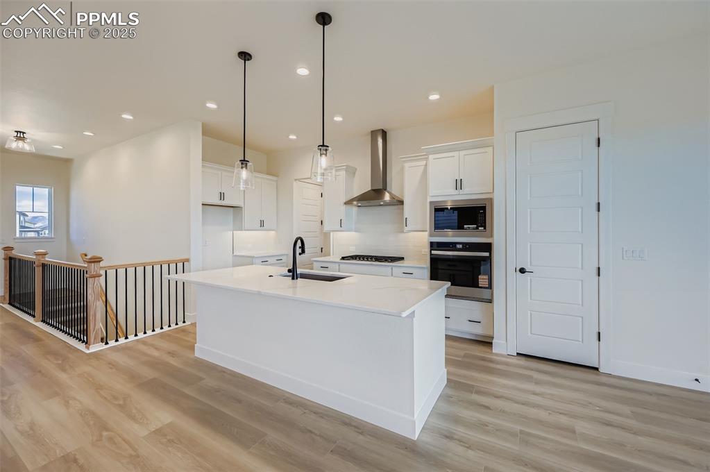 Image 6 of 28: Kitchen with white cabinetry, a kitchen island with sink, appliances with s