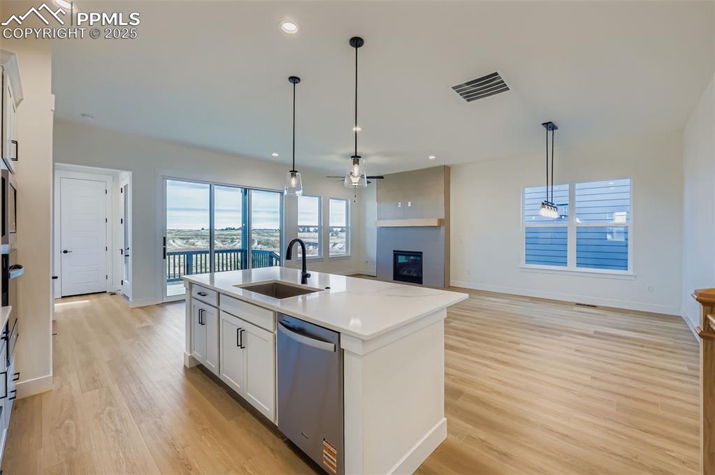 Image 8 of 28: Kitchen featuring white cabinets, a fireplace, open floor plan, decorative