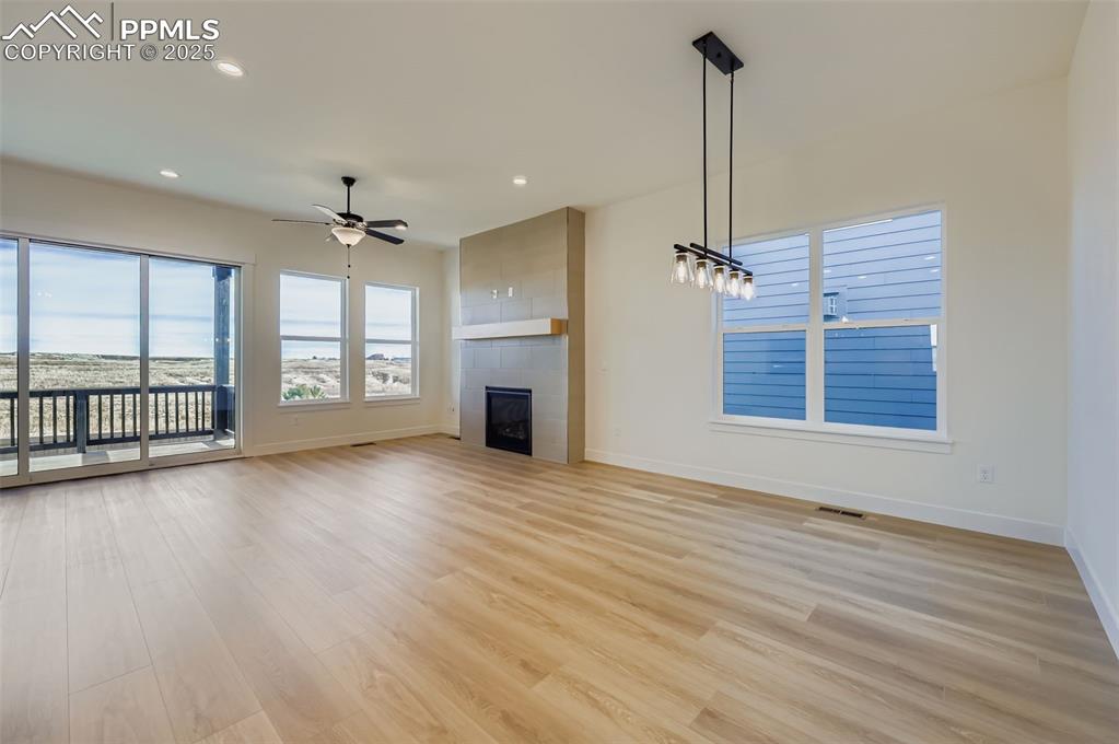 Image 9 of 28: Unfurnished living room with recessed lighting, a fireplace, light wood-sty