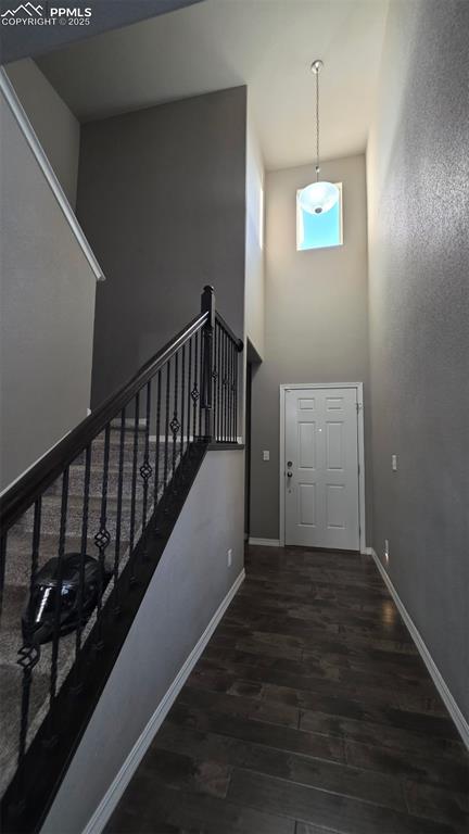Image 3 of 8: Entryway with a towering ceiling, stairway, and dark wood-style flooring
