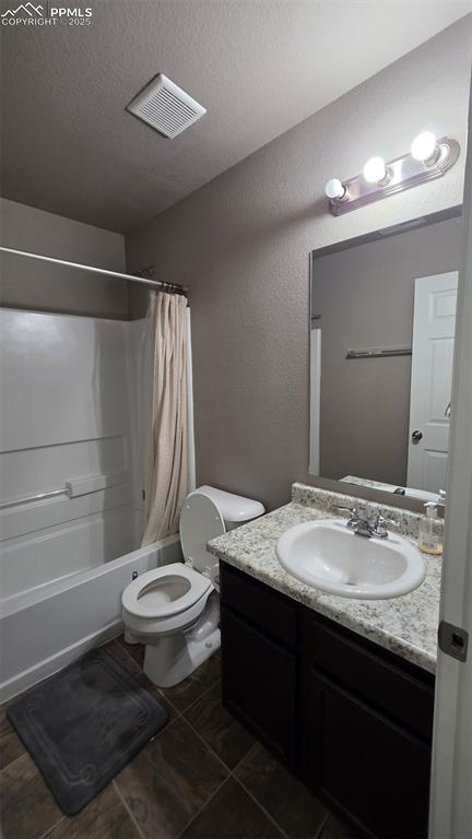 Image 5 of 8: Full bathroom with a textured wall, shower / bath combination with curtain,