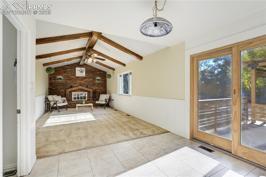 Image 15 of 50: Den with wood beam vaulted ceiling and grand fireplace