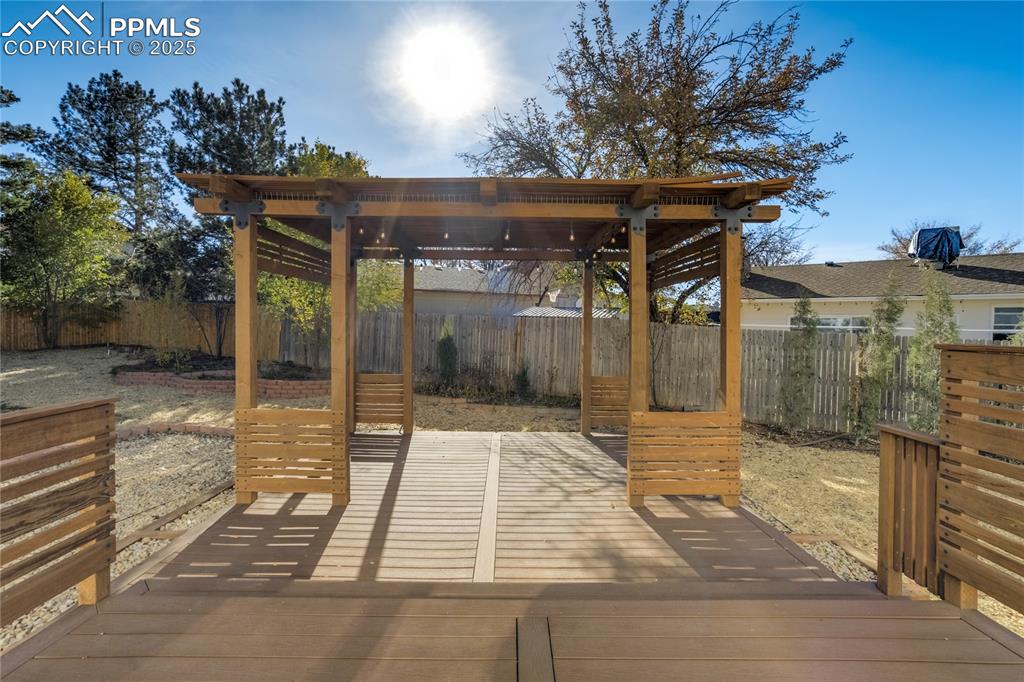 Image 45 of 50: Fully fenced backyard with custom 2-tier deck with pergola