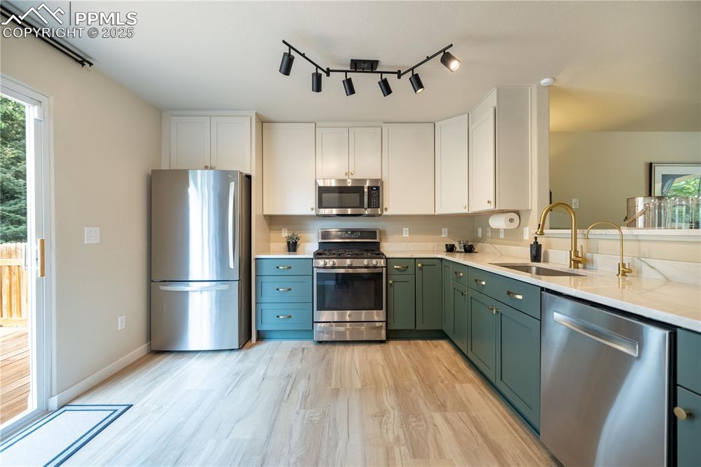 Image 12 of 42: Kitchen featuring appliances with stainless steel finishes, green cabinets,