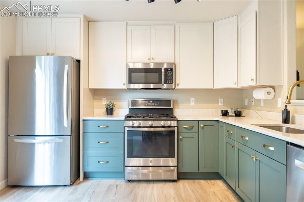 Image 13 of 42: Kitchen featuring stainless steel appliances, green cabinetry, white cabine