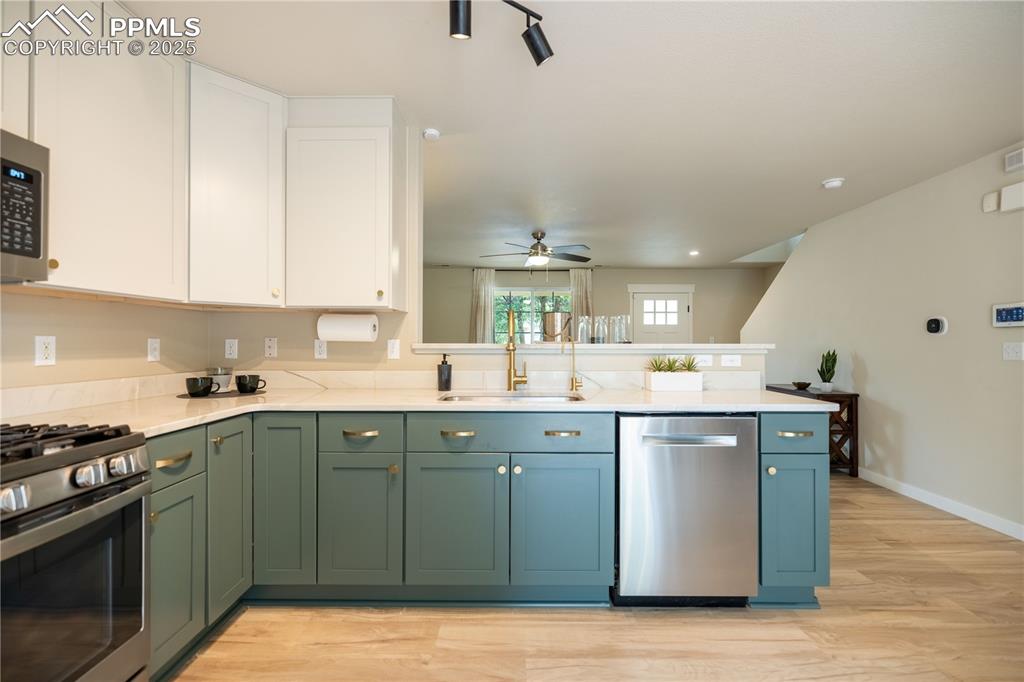 Image 15 of 42: Kitchen with green cabinets, stainless steel appliances, white cabinets, a 