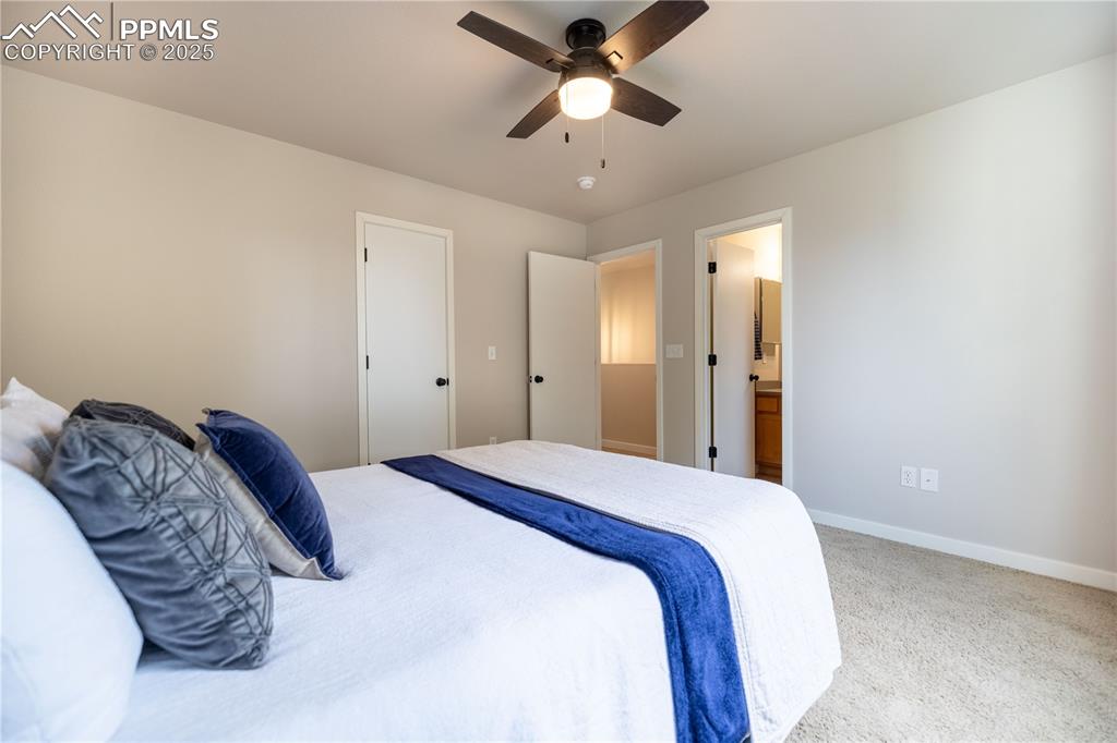 Image 22 of 42: Carpeted bedroom featuring a ceiling fan and ensuite bathroom