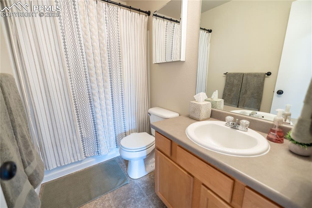 Image 30 of 42: Full bathroom featuring vanity, tile patterned flooring, and curtained show