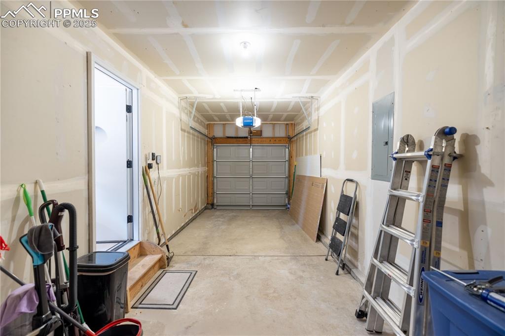 Image 32 of 42: Garage with electric panel and a garage door opener