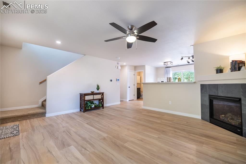 Image 5 of 42: Unfurnished living room with a tile fireplace, light wood-style flooring, c