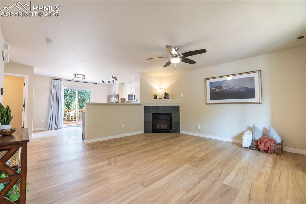 Image 8 of 42: Living room featuring light wood finished floors, a ceiling fan, and a tile